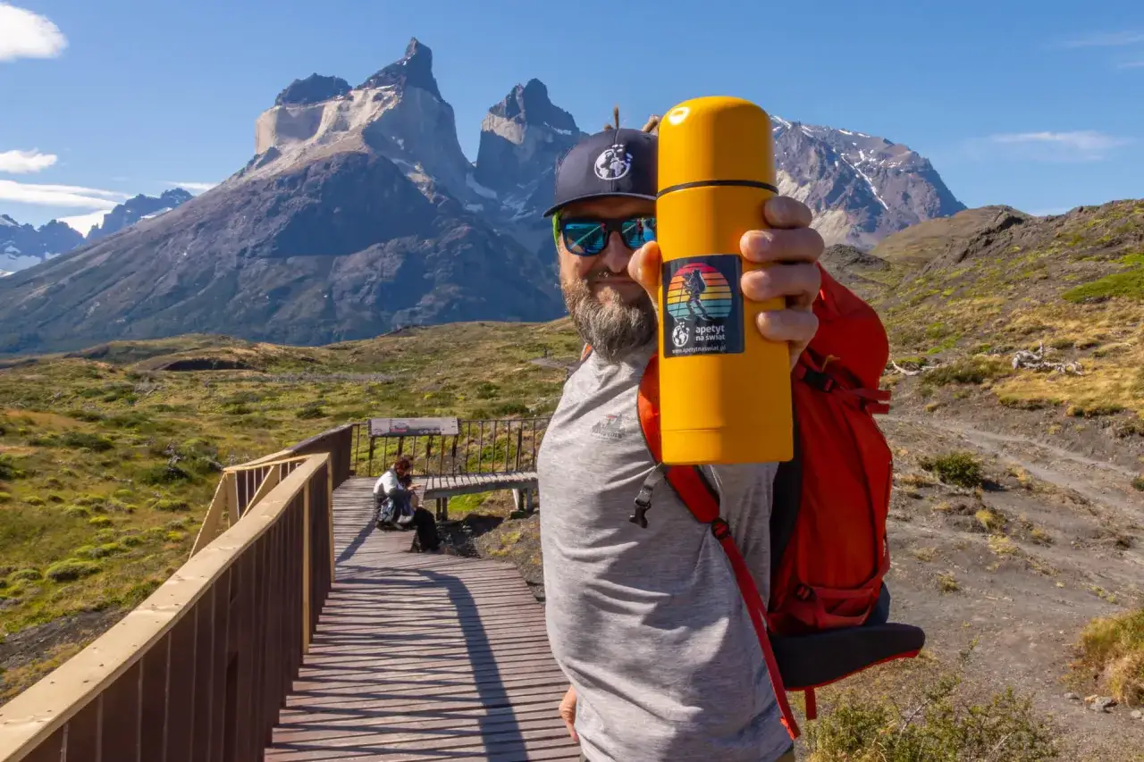 Mężczyzna z żółtym termosem na tle majestatycznych gór. To z pewnością Patagonia, a nie Alzacja.