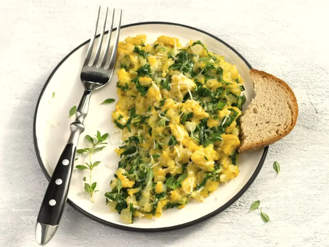 Jajecznica ze szpinakiem i serem, idealna na zdrowe przepisy na śniadanie. Podana z kromką chleba i gałązkami ziół.