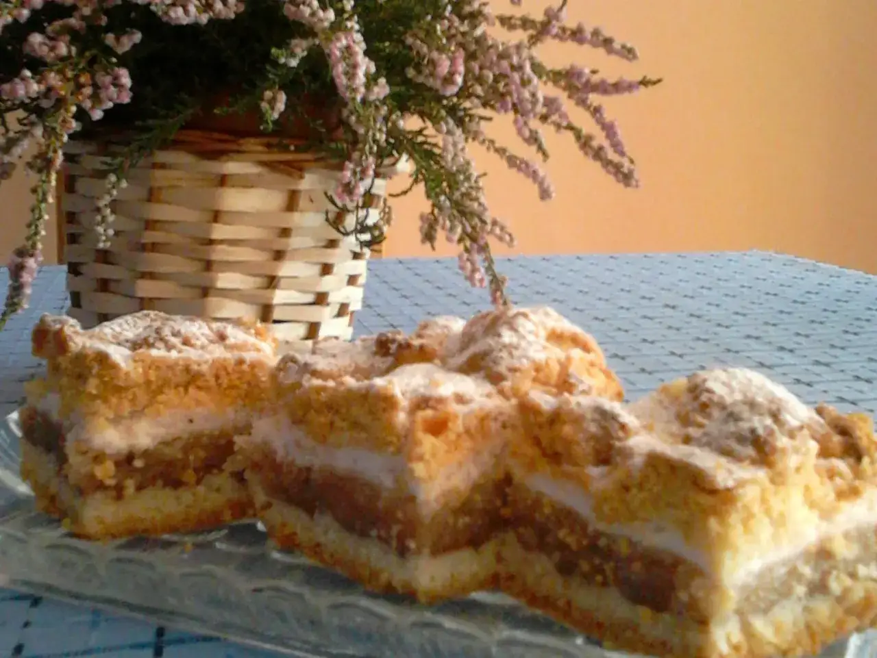 Pyszna szarlotka na talerzu, która nie opadła! Idealna na deser, z koszykiem wrzosów w tle.