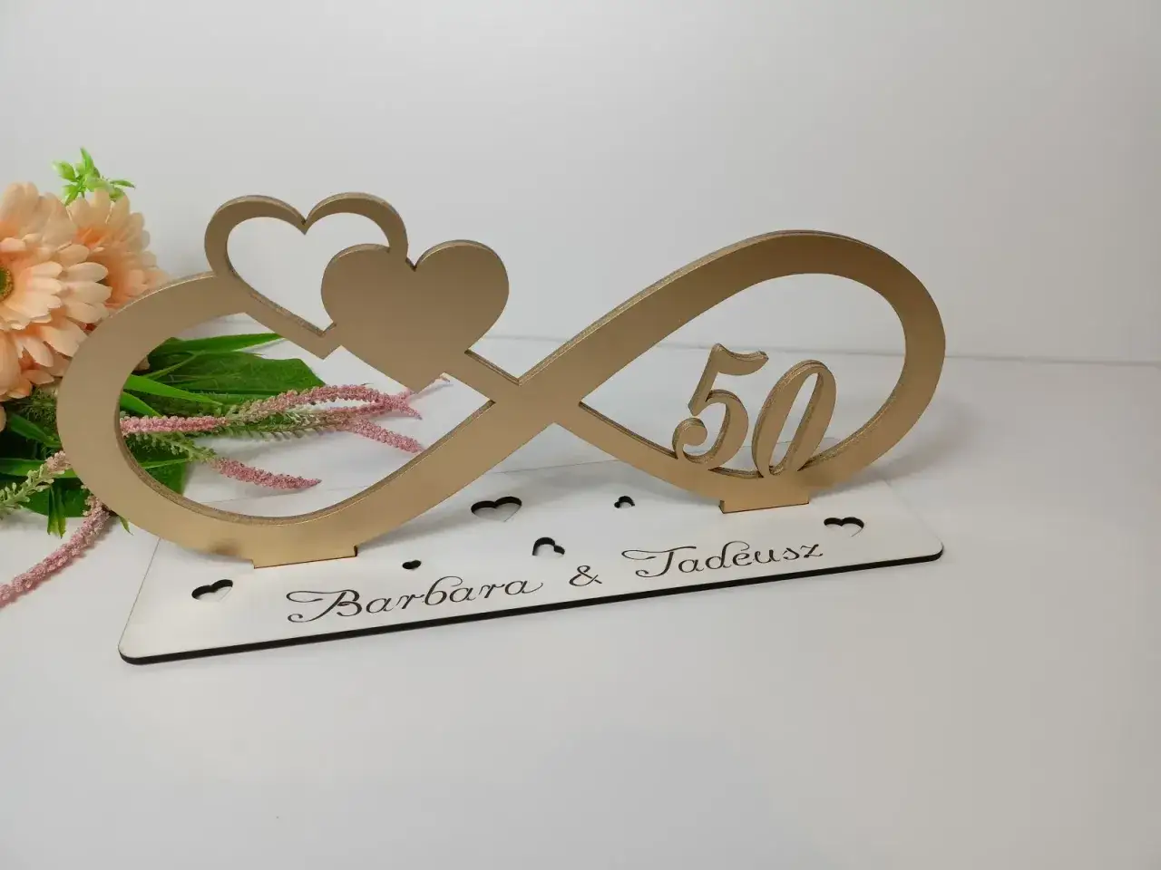 Złoty symbol nieskończoności z sercami i cyfrą 50. Na podstawie wygrawerowane imiona Barbara & Tadeusz. Idealna dekoracja na 50 rocznicę ślubu.