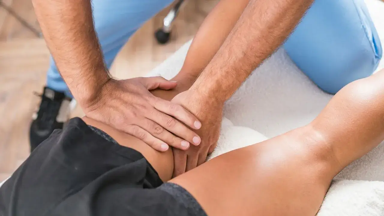 Fizjoterapeuta masuje udo pacjenta. Zastanawiasz się, ile godzin trwa etat fizjoterapeuty?