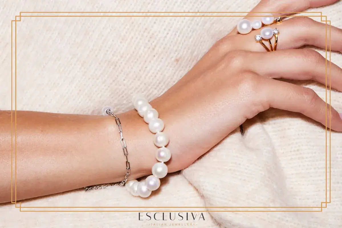 Dłoń ozdobiona bransoletką z pereł i pierścionkiem z brylantami. Poznaj, jak rozpoznać prawdziwe perły.
