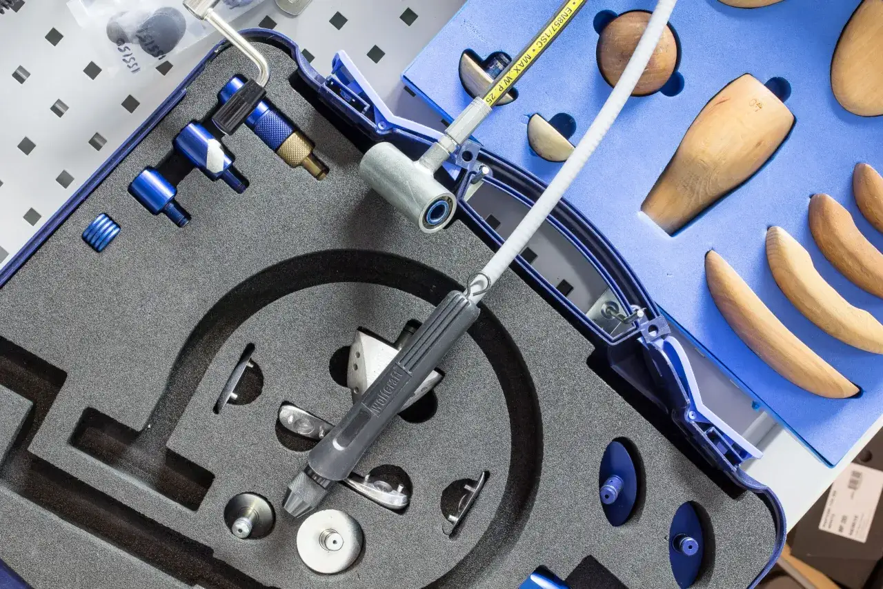 Zestaw narzędzi do odbarczania butów narciarskich, z drewnianymi kopytami i precyzyjnymi elementami.