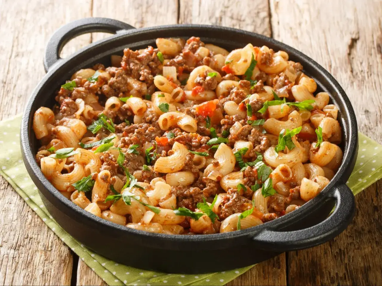 Pyszne danie z makaronem i mielonym mięsem w sosie pomidorowym. Idealne co z mielonego na obiad, posypane świeżą natką pietruszki.