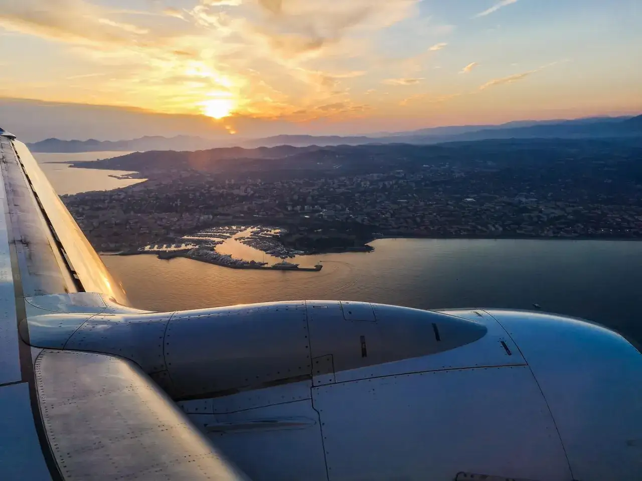 Widok z samolotu na wybrzeże Włoch o zachodzie słońca. Czy loty do Włoch są bezpieczne? Tak, ten widok potwierdza, że podróż jest warta zachodu.