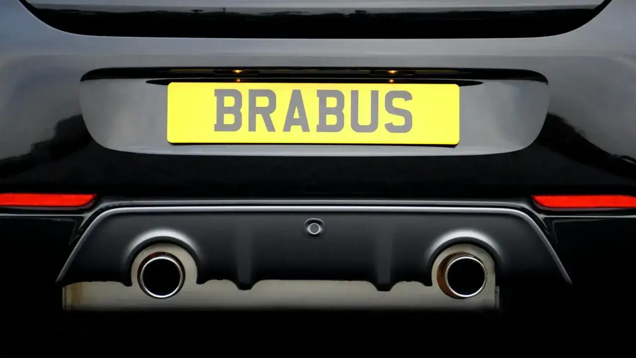 Tył czarnego samochodu z żółtą tablicą rejestracyjną "BRABUS" i podwójnymi końcówkami wydechu.