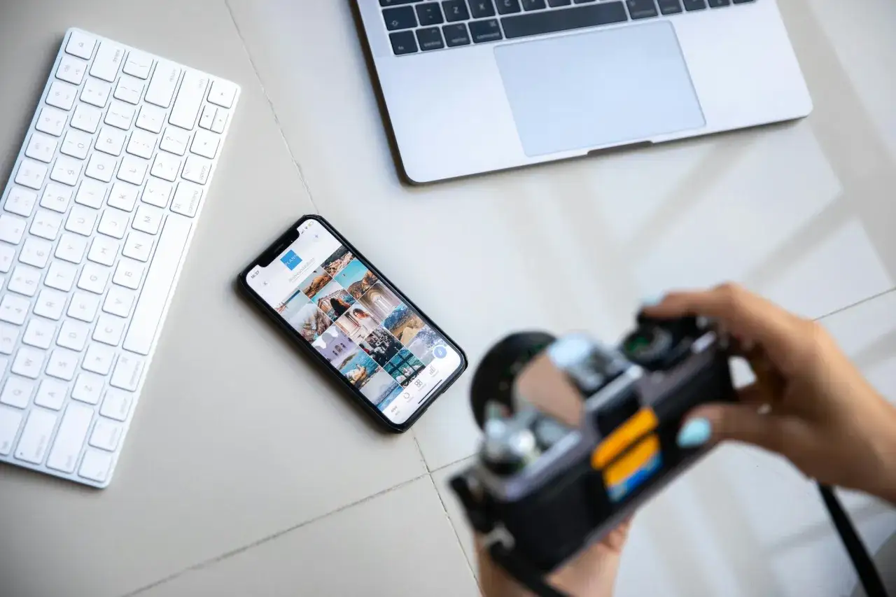 Aparat fotograficzny służy do uwieczniania chwil. Obok klawiatury, telefonu z Instagramem i laptopa, jest gotowy do pracy.