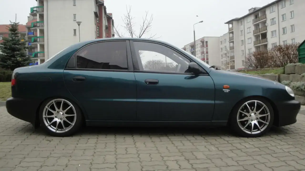 Zielony Lanos z przyciemnianymi szybami i srebrnymi felgami wieloramiennymi.