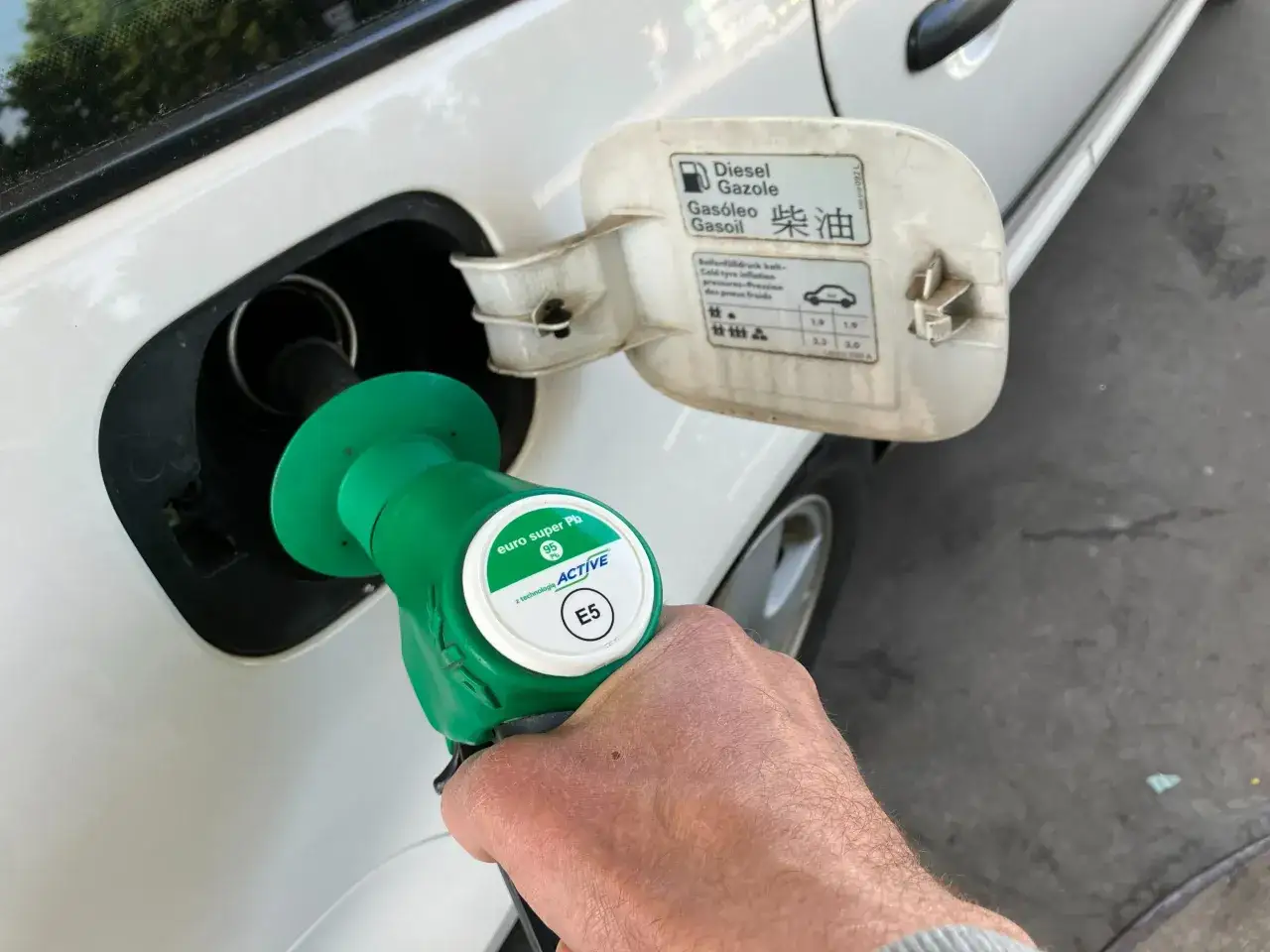 Zielony pistolet z napisem "euro super Pb 95 E5" jest wkładany do baku samochodu. Czy pistolet od benzyny wejdzie do diesla? Na klapce baku widnieje napis "Diesel".