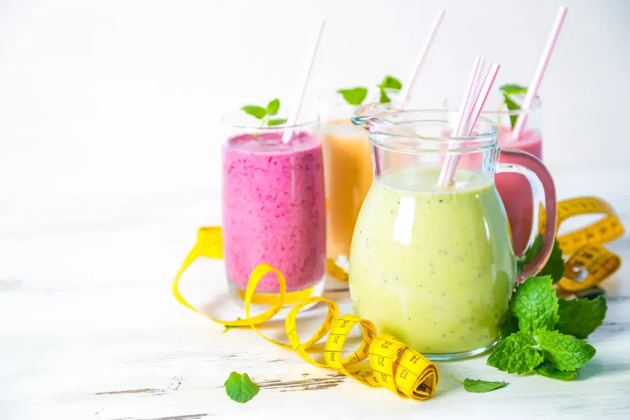 Kolorowe smoothie odchudzające przepisy w dzbanku i szklankach, ozdobione miętą i taśmą mierniczą.