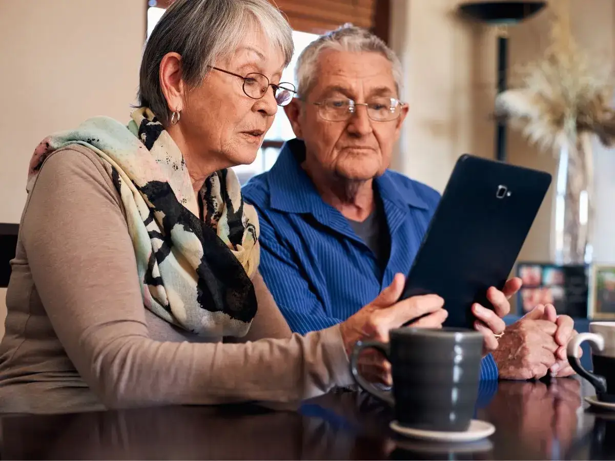Starsza para szuka informacji: karta seniora jak wyrobić. Na tablecie przeglądają zasady.