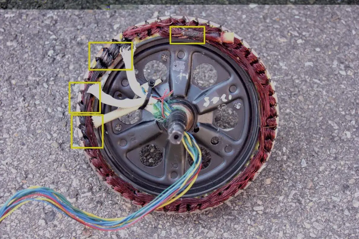 Uszkodzony silnik przekładniowy z widocznymi przepalonymi uzwojeniami i kablami.