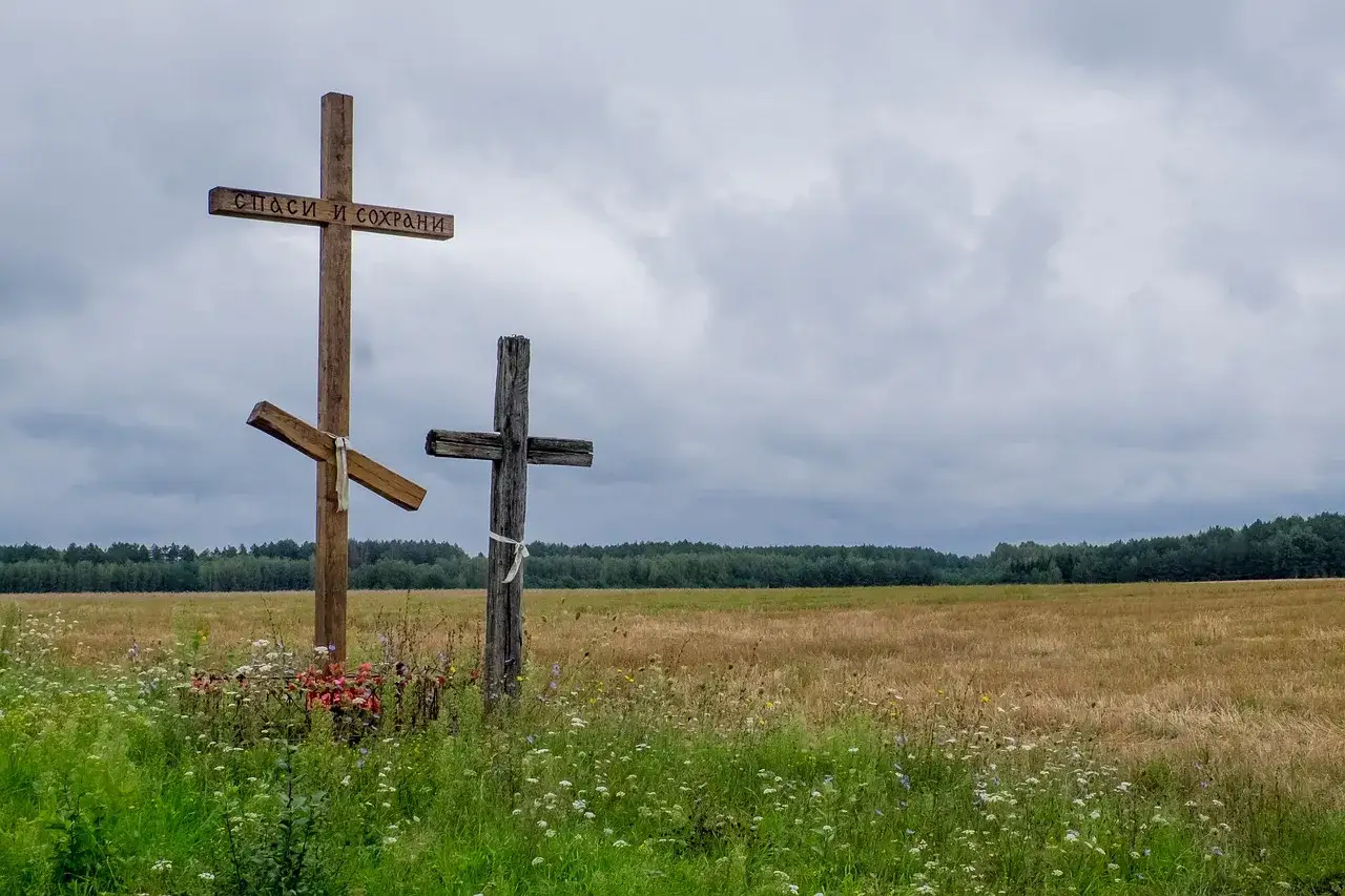 Trzy krzyże na tle pola i lasu. Jeden z nich ma napis "Spasi i Sochrani". Czy horoskopy to grzech?