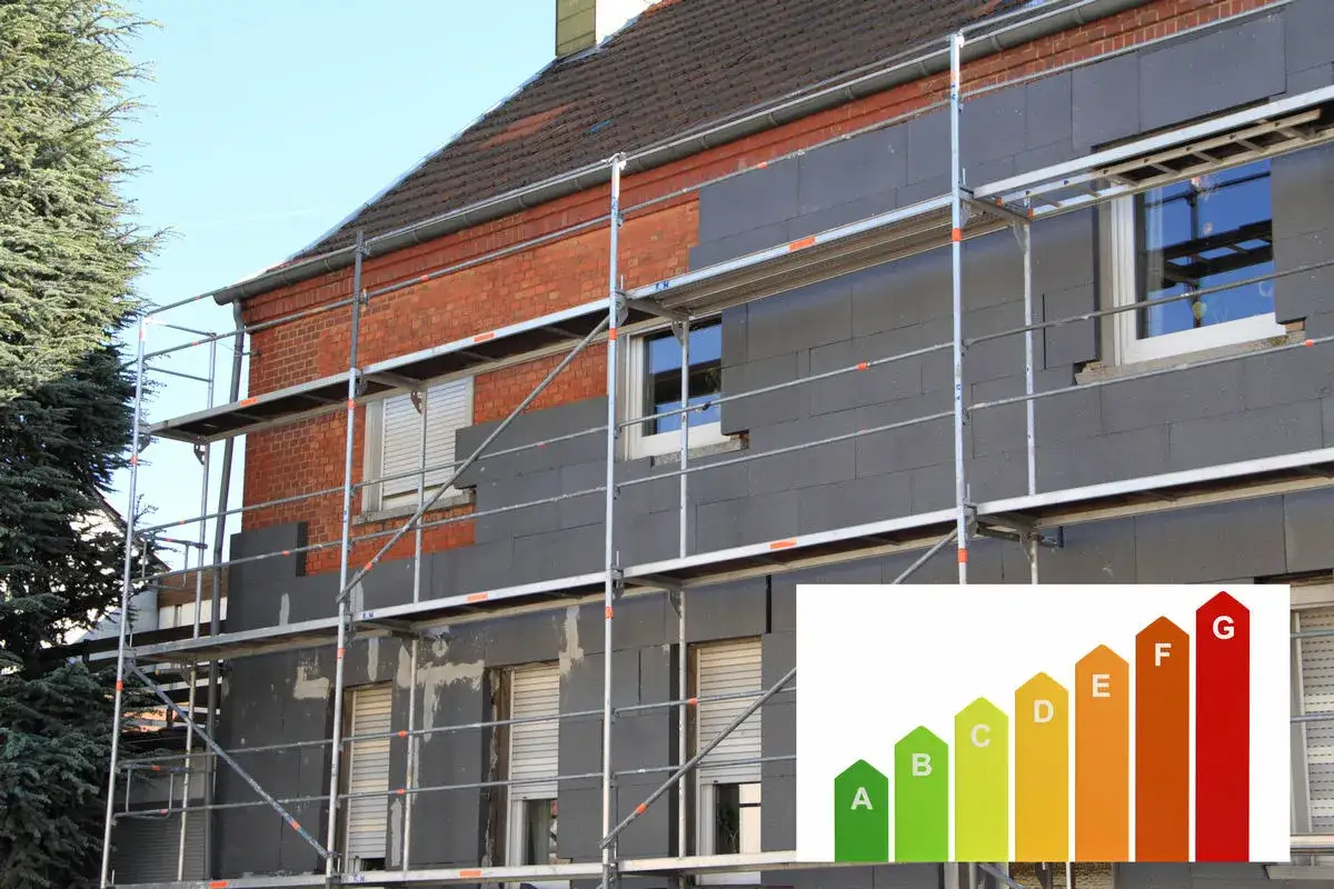 Dom w trakcie ocieplenia domów. Scaffolding otacza budynek, na którym montowane są płyty izolacyjne. W rogu wstawka z klasą energetyczną.