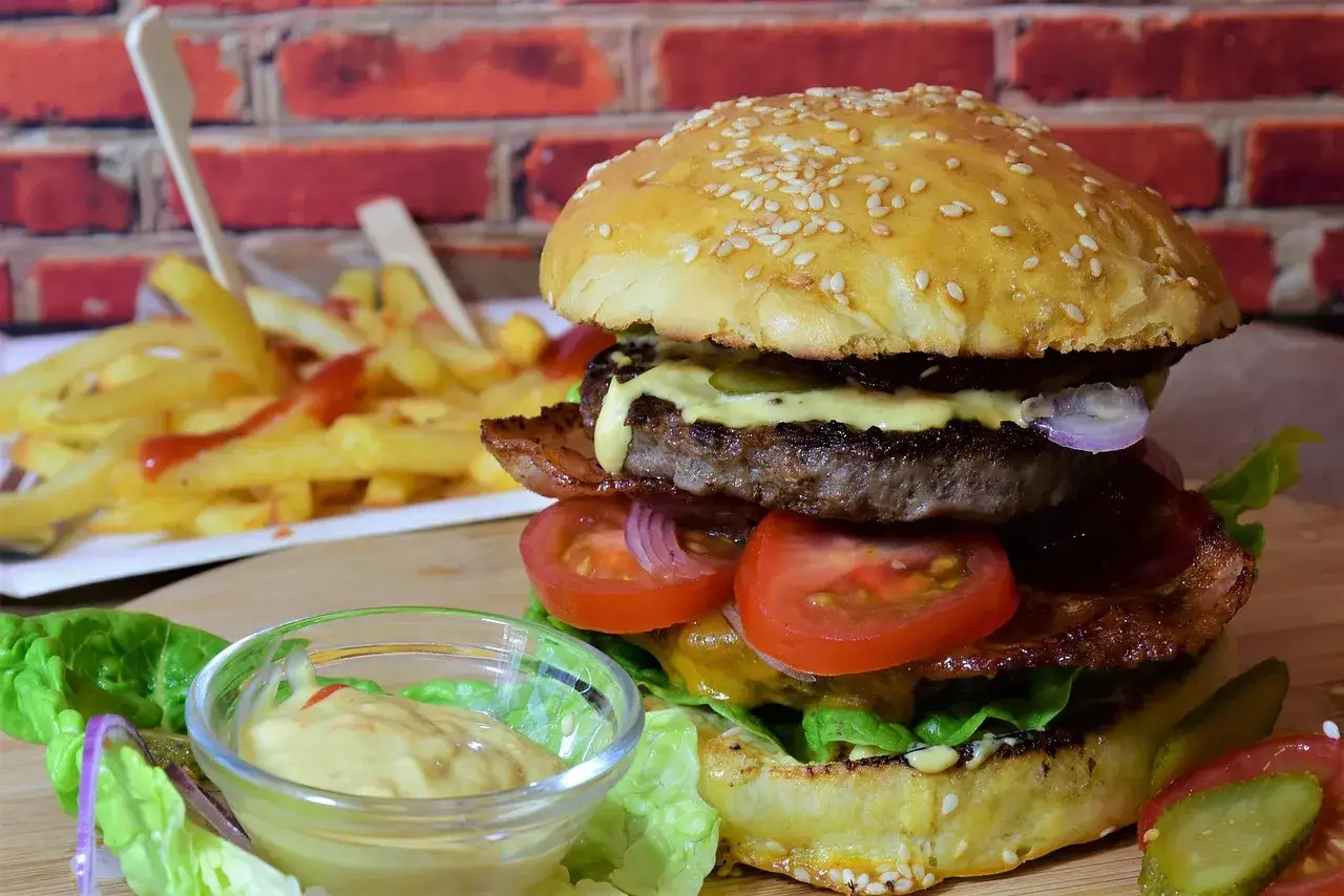 Soczysty burger z wołowiny, idealne jakie mięso do burgerów, z dodatkami i frytkami w tle.
