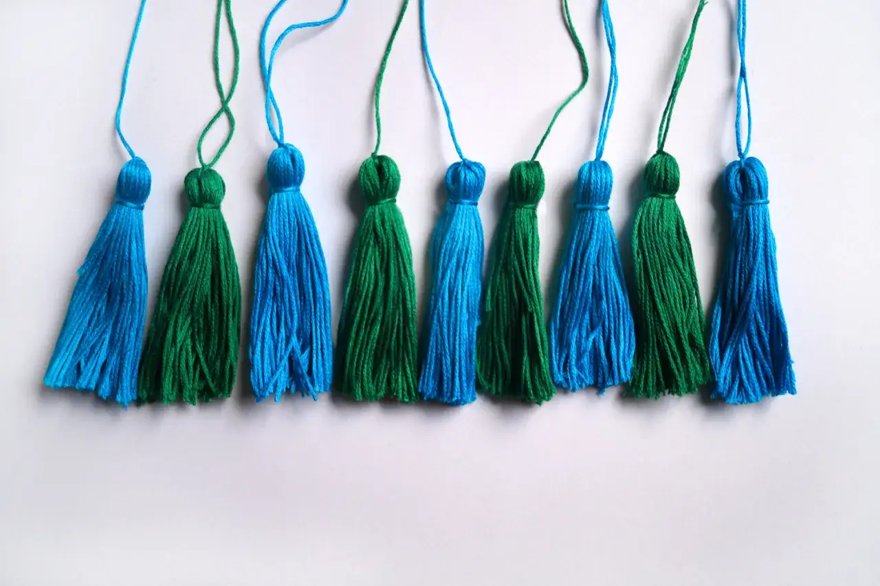 Niebieskie i zielone chwosty z muliny, idealne do ozdabiania, tworzenia biżuterii lub jako breloczki.