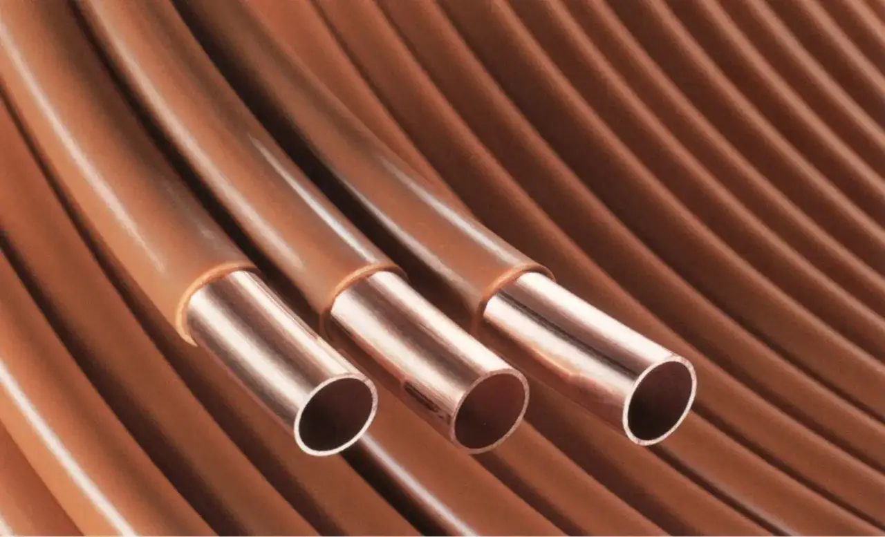 Trzy miedziane rury, idealne do instalacji wody ciepłej i zimnej, zwinięte w harmonijkę.