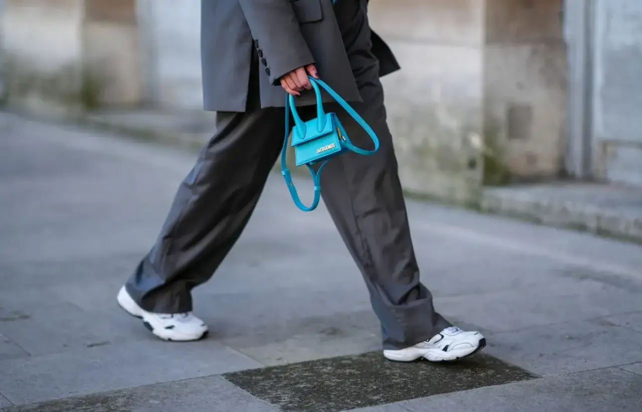 Elegancki damski garnitur w połączeniu z białymi sneakersami i turkusową torebką.