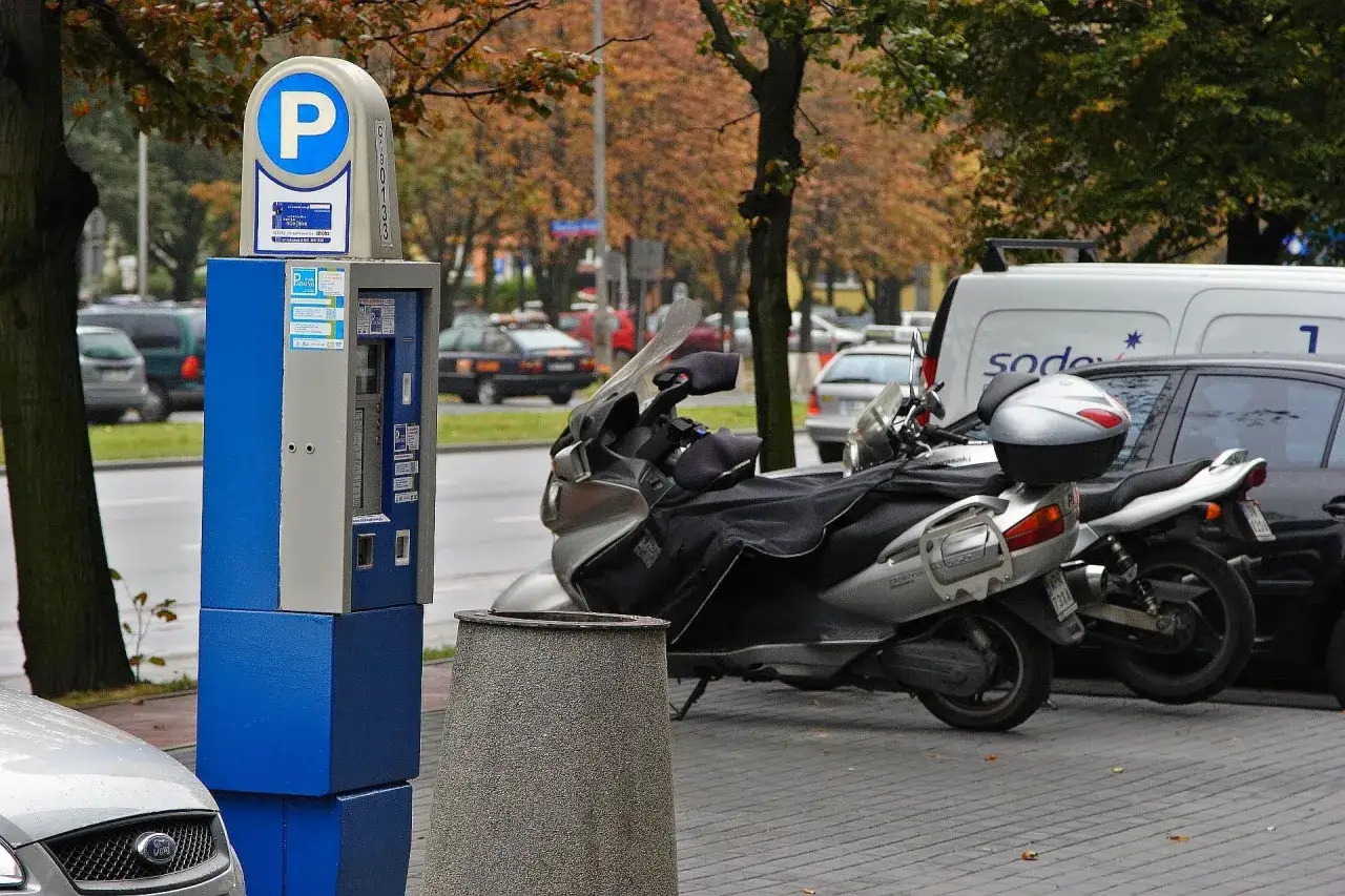 Parkomat z symbolem "P" i skuterem obok. Upewnij się, że masz ważny bilet, by uniknąć mandatu za parkowanie.