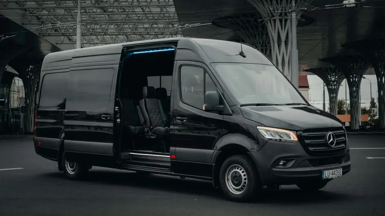 Czarny Mercedes Sprinter z otwartymi drzwiami, wnętrze z wygodnymi fotelami. Zastanawiasz się, ile kosztuje bus do Francji?
