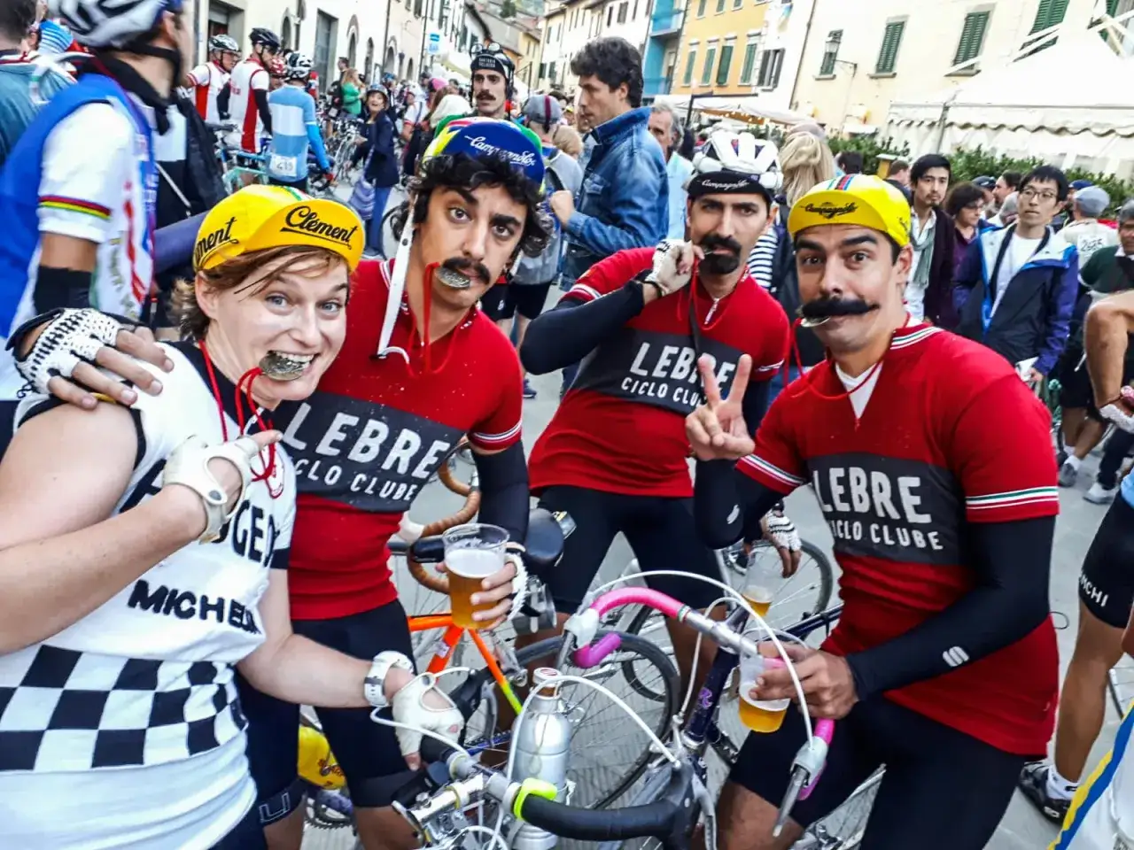 Uczestnicy wyścigu kolarskiego we Włoszech, z medalami na szyjach i piwem w rękach, świętują po zawodach.