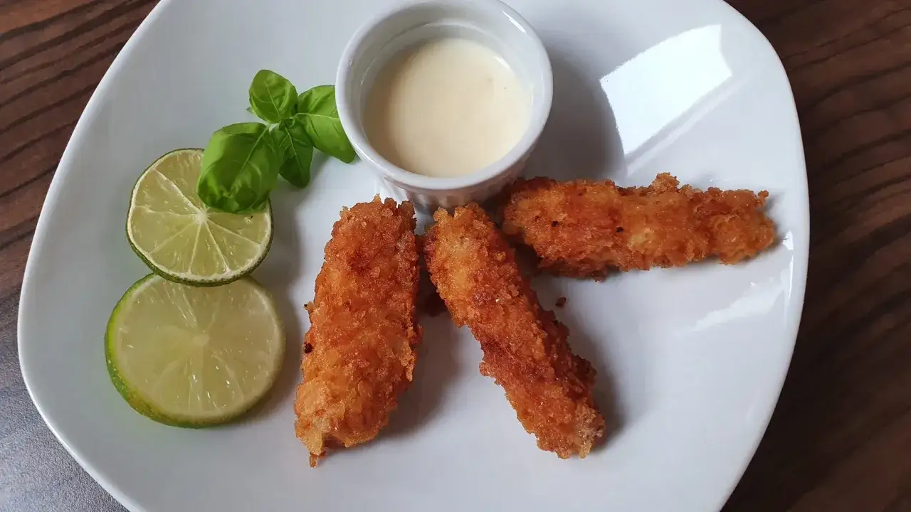 Chrupiąca ryba w panko, podana z sosem i limonką, wygląda apetycznie.