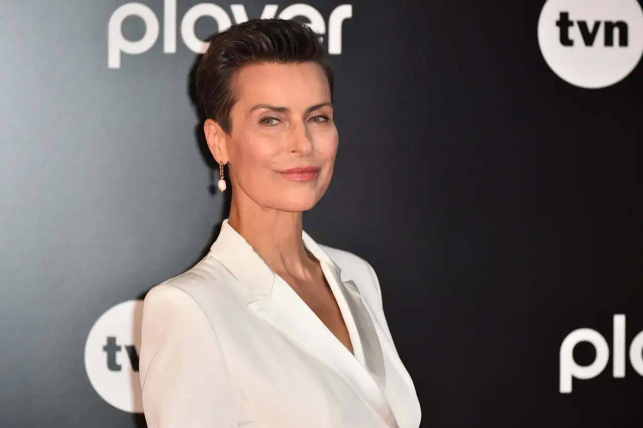 Danuta Stenka w białej kreacji, gwiazda filmów, seriali i programów, na tle logo TVN i Playera.