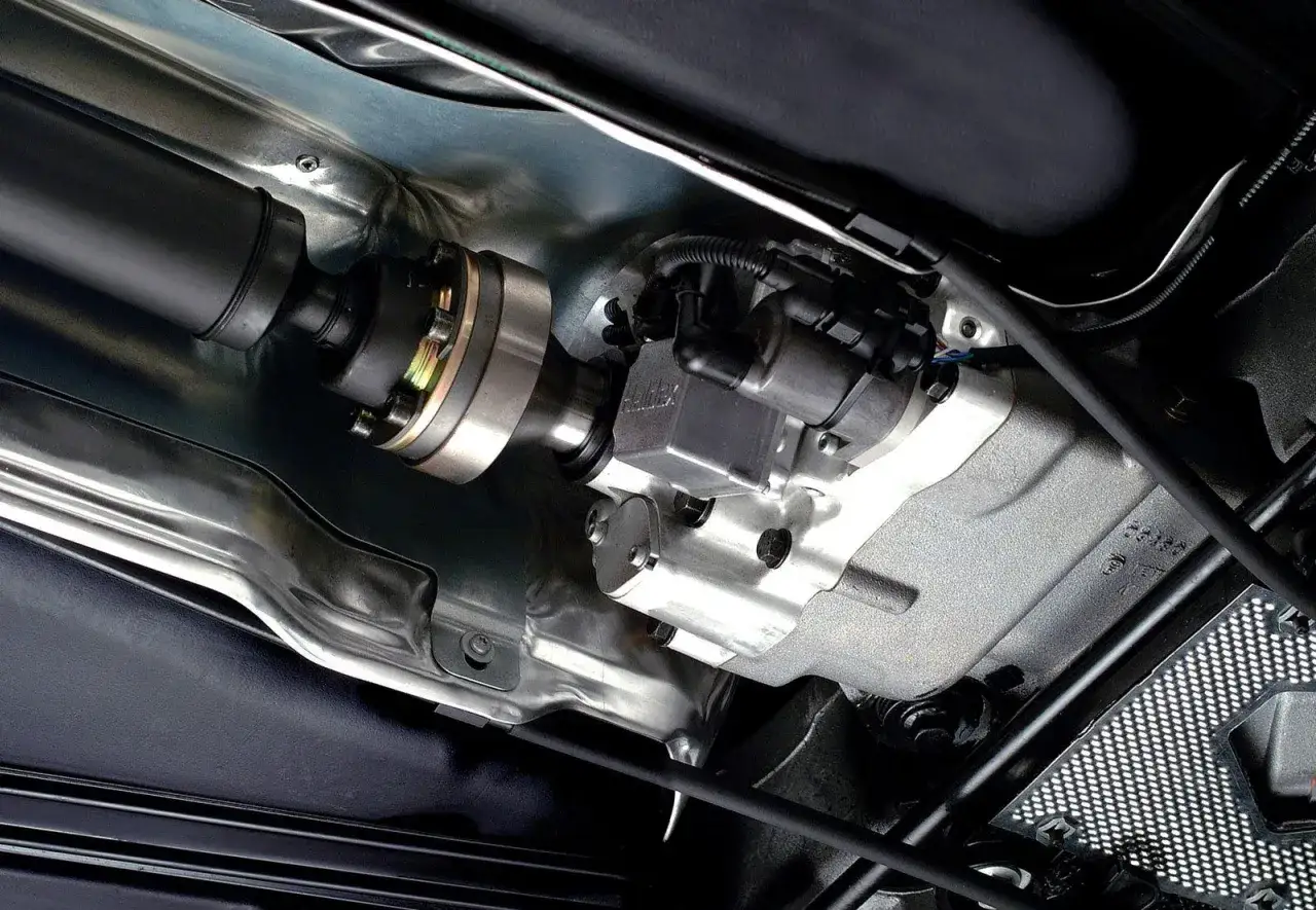 Widok od spodu pojazdu na wał napędowy i moduł Haldex. Pamiętaj o regularnej wymianie oleju w haldexie, aby zapewnić jego prawidłowe działanie.