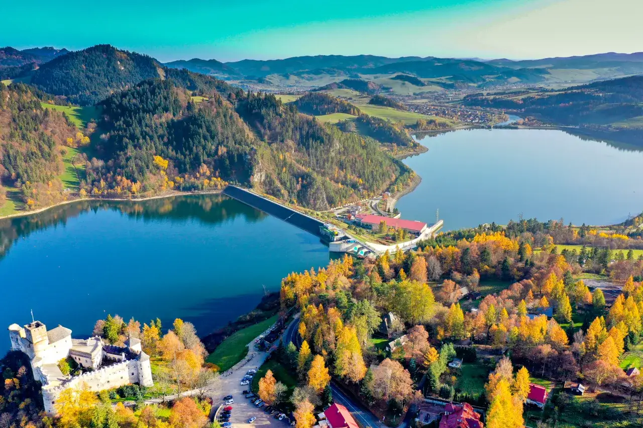 Widok z lotu ptaka na zamek w Niedzicy, Jezioro Czorsztyńskie i jesienne lasy.
