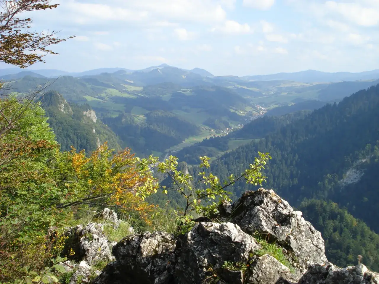 Widok z bacówki Trzy Korony na malowniczą dolinę Pienin. W oddali widać góry i lasy.