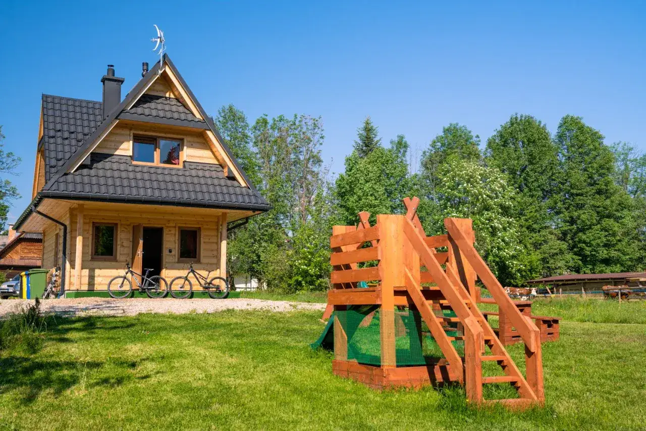 Drewniany domek w Bukowinie Tatrzańskiej z placem zabaw i rowerami przed wejściem. Idealne miejsce na rodzinne wakacje.
