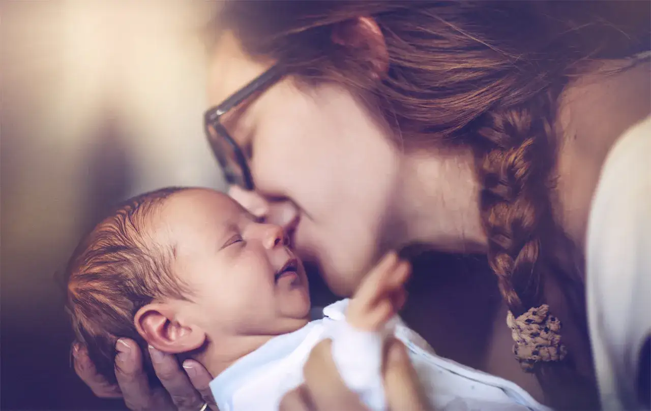 Delikatny pocałunek matki w czoło noworodka. Czy dziecko musi być zameldowane tam gdzie rodzice?