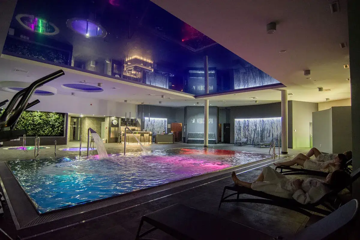 Relaks w hotelowym spa w Wielkopolsce. Basen z kolorowym podświetleniem, wodospady i leżaki.