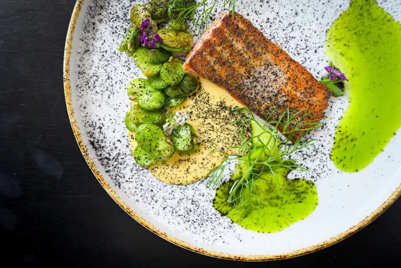 Łosoś z fasolką szparagową, musem i zielonym sosem na talerzu.