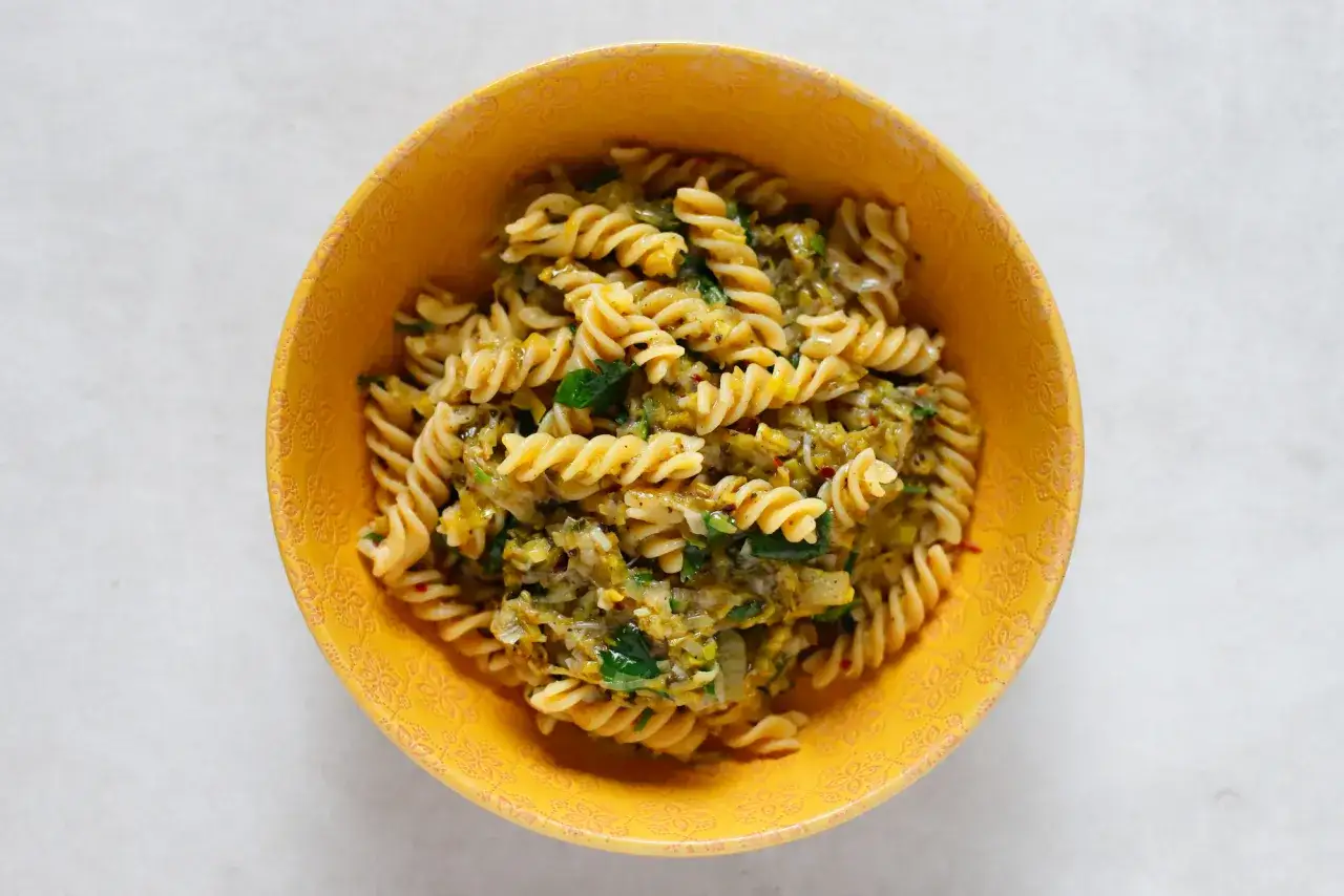 Fusilli z porem i zielonymi ziołami w żółtej misce. Pyszny makaron z porem, idealny na szybki obiad.