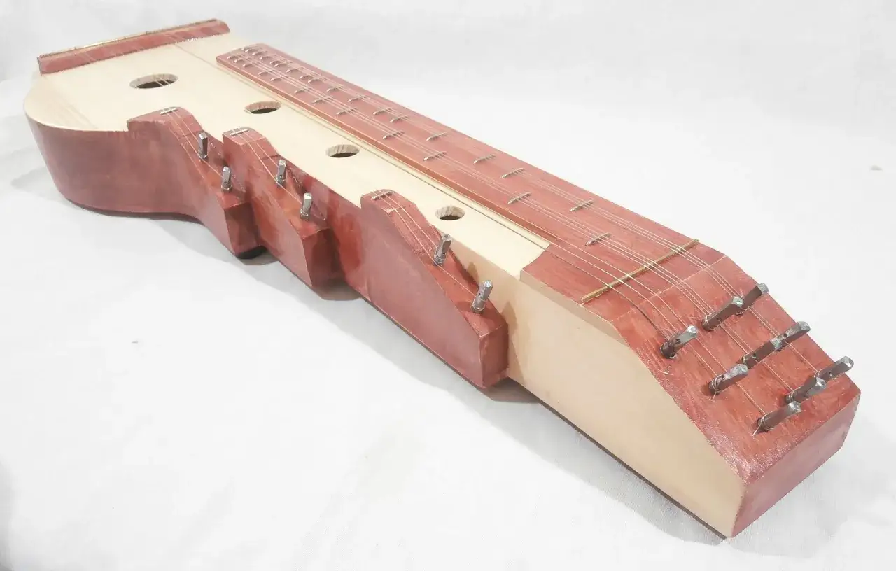 Drewniana cytra instrument z wieloma strunami i otworami rezonansowymi.