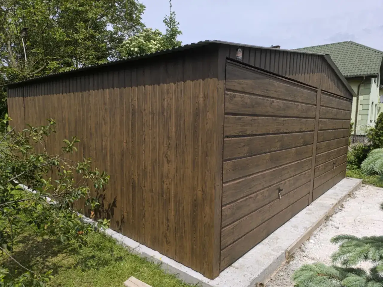 Brązowy garaż blaszany z drzwiami uchylnymi. Warto zadbać o to, jak pozbyć się wilgoci w garażu blaszanym, by chronić przechowywane rzeczy.