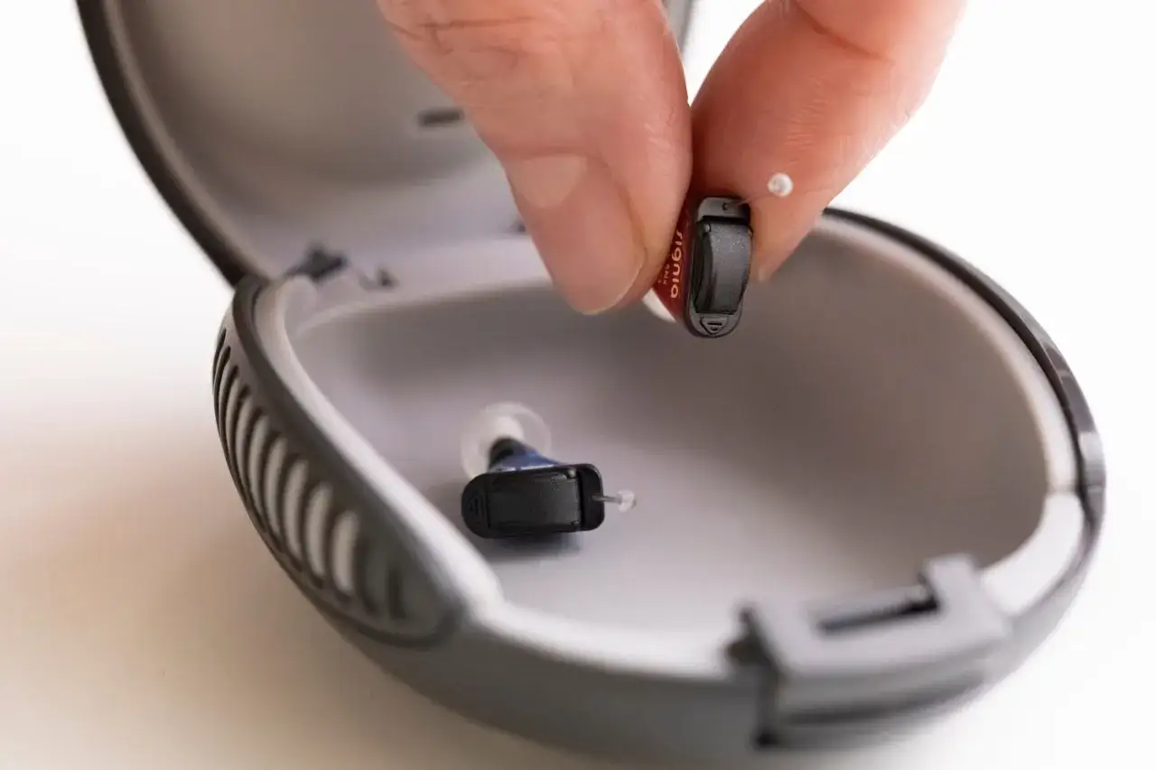 Dłoń wkłada aparat słuchowy do etui. Tabletki osuszające do aparatów słuchowych jak używać - dbaj o swoje aparaty.