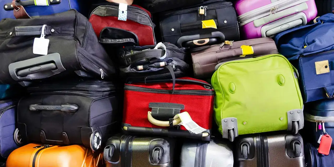 A large pile of various suitcases and bags in different colors, stacked high.