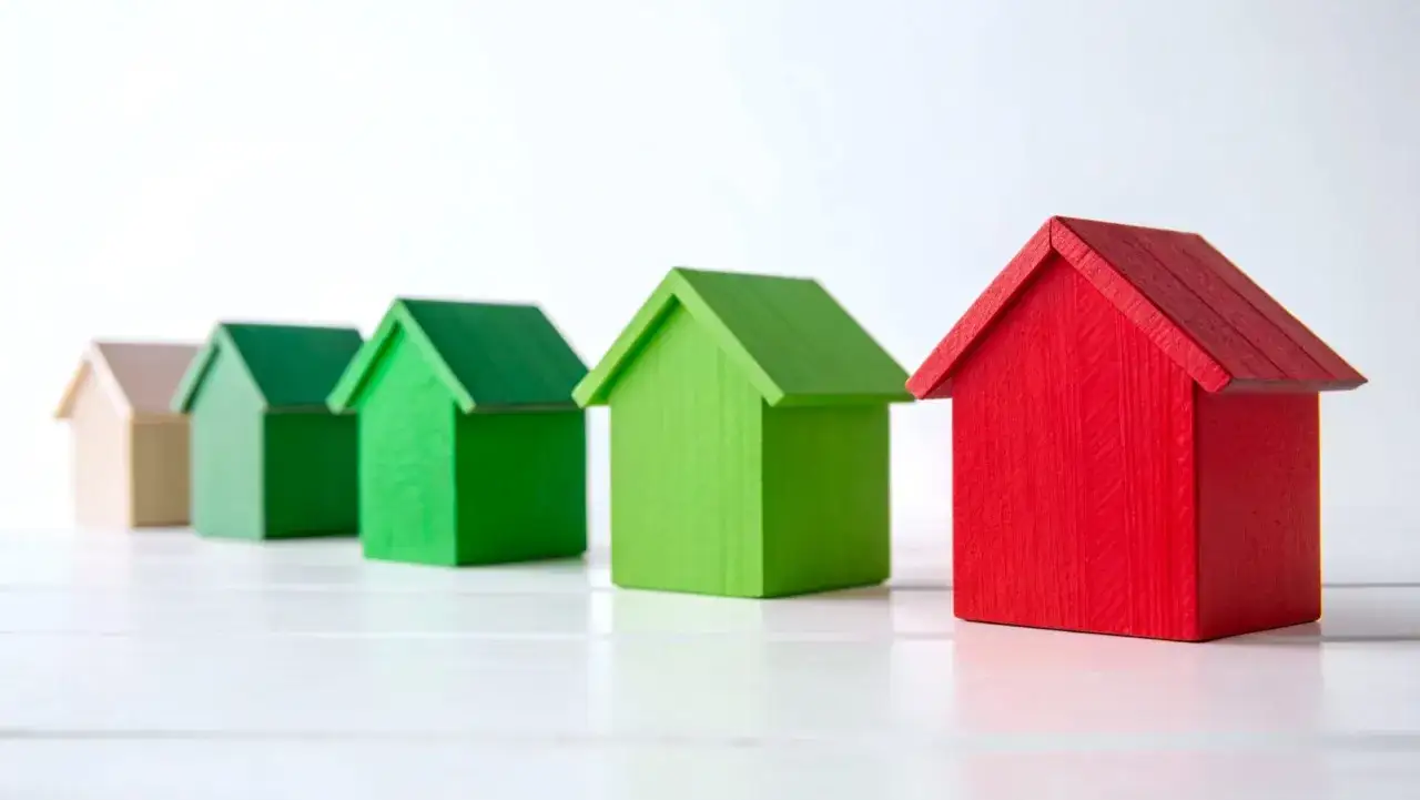 Rząd domków: beżowy, zielony, zielony, zielony, czerwony. Symbolizują różne poziomy klasy energetycznej.