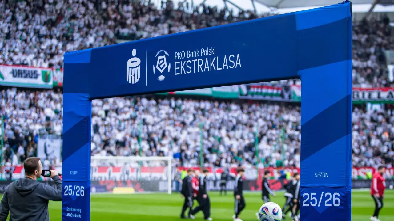Brama z logo PKO Bank Polski Ekstraklasa na tle stadionu i kibiców. Sezon 25/26.