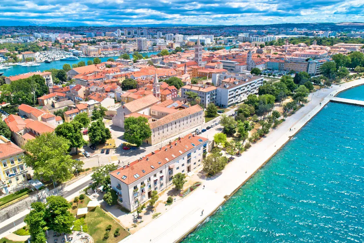 Zadar w czerwcu: słoneczna pogoda nad Adriatykiem, widok na miasto z czerwonymi dachami, promenadę i turkusowe morze.