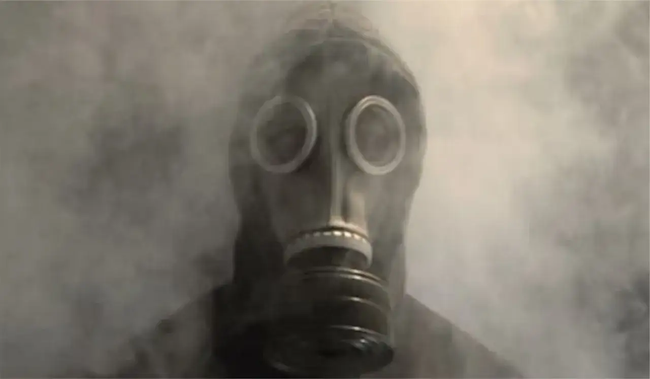 Osoba w masce gazowej otoczona dymem.