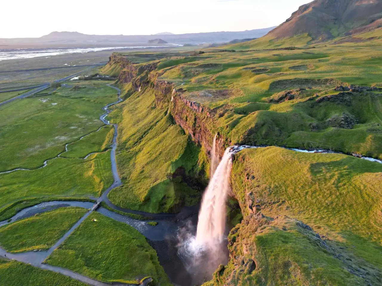 Wodospad Seljalandsfoss na Islandii w złotym świetle zachodzącego słońca.