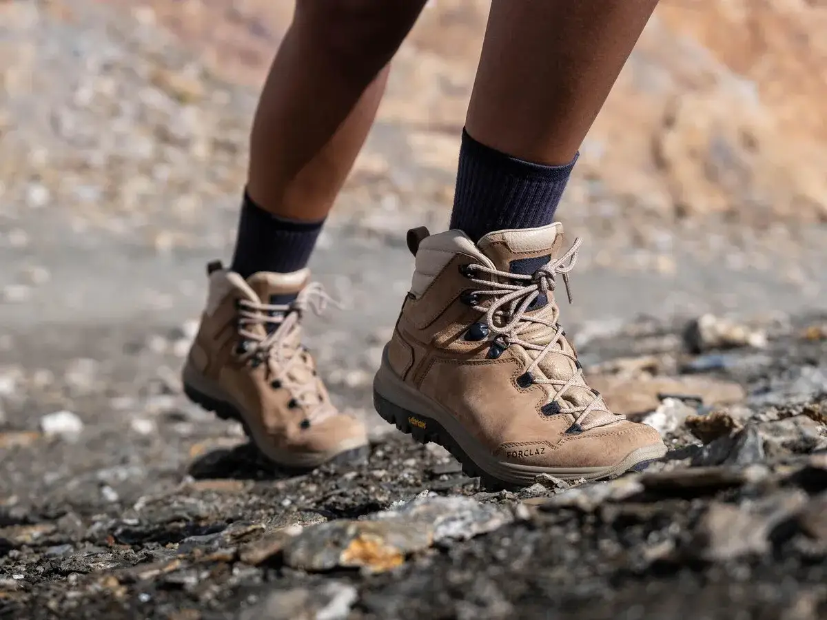 Botas de montaña Forclaz de color marrón, con cordones, sobre terreno rocoso.