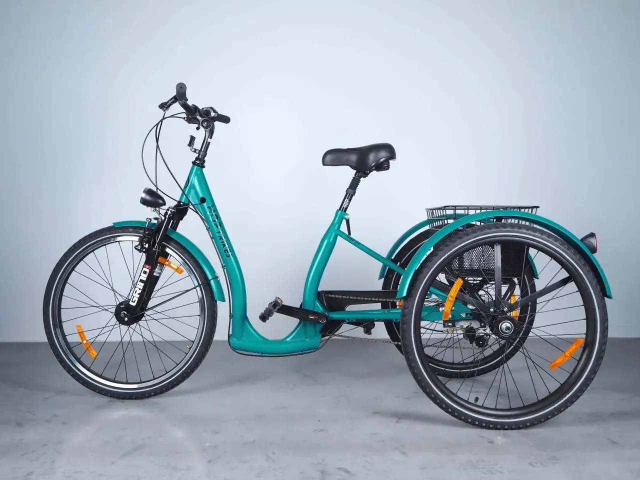 Turkusowy rower trójkołowy, idealny jako rower dla niepełnosprawnych, z koszykiem z tyłu i przednim światłem.