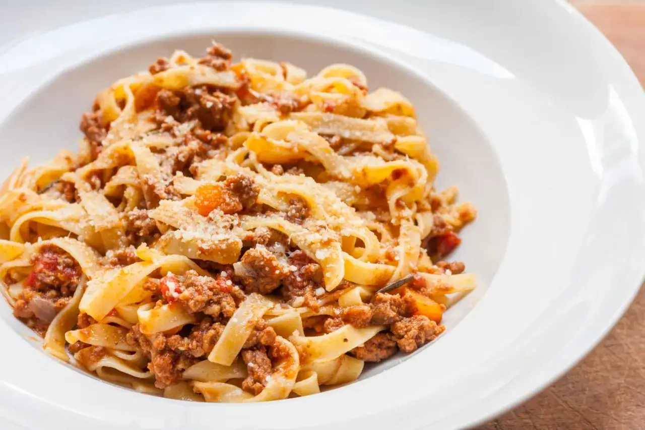 Tagliatelle z bogatym, mięsnym sosem bolońskim, posypane parmezanem. Pyszne danie, które zadowoli każdego miłośnika włoskiej kuchni.