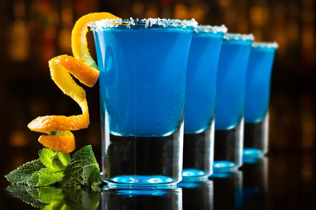 Niebieskie shoty Kamikaze, z pomarańczową skórką i miętą. Idealne, gdy nie masz blue curacao.