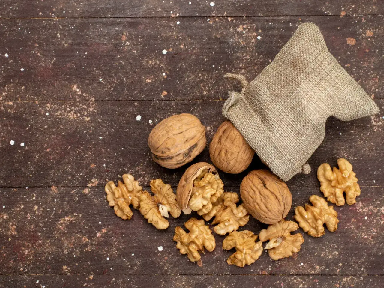 Orzechy włoskie w łupinach i połówki, wysypane z worka. Czy orzechy włoskie można mrozić? Tak, mrożenie to świetny sposób na ich przechowywanie.