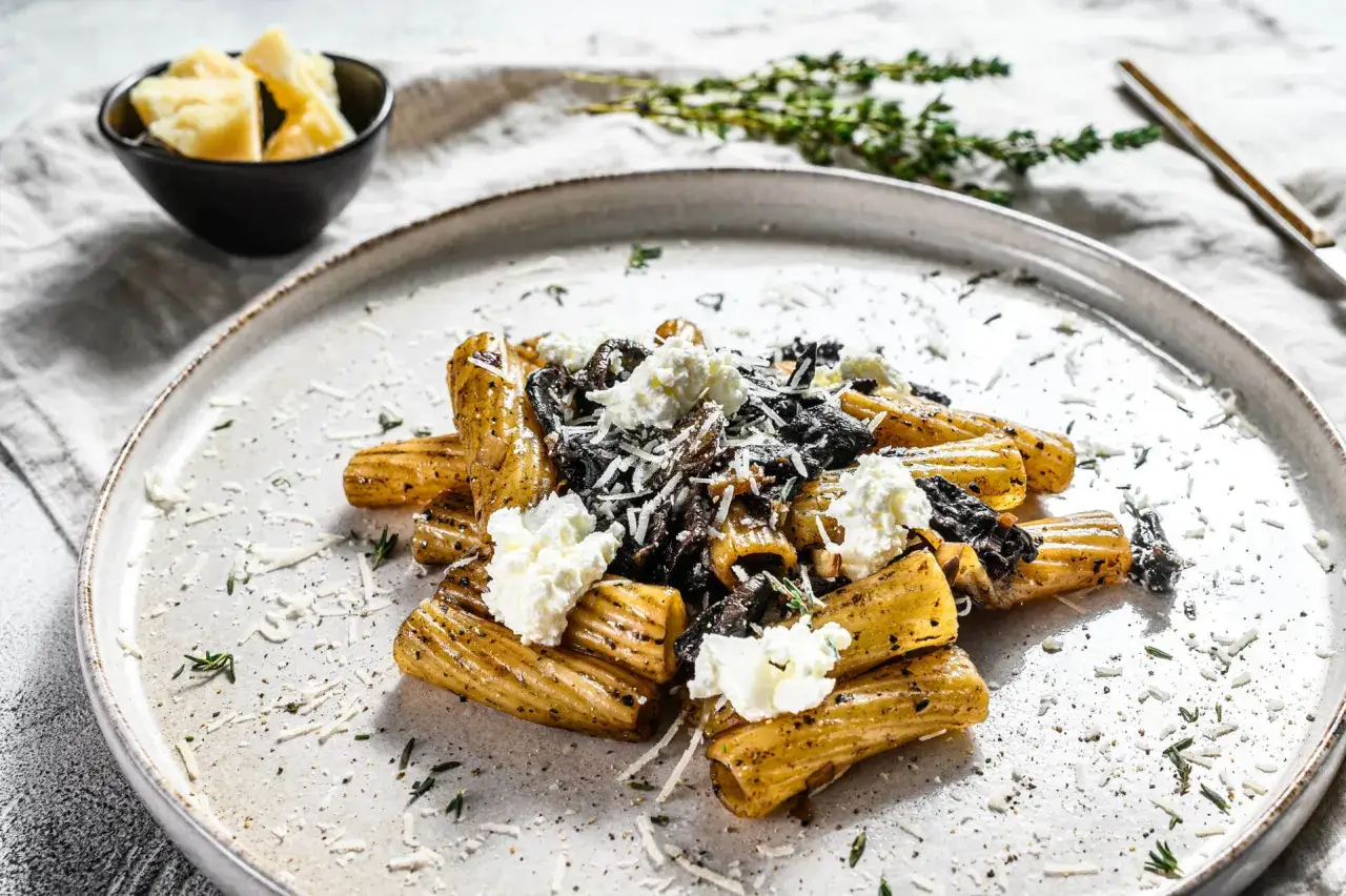 Makaron z pastą truflową, udekorowany kremowym serem i tartym parmezanem, pachnie obłędnie.